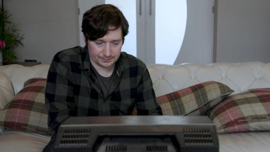 A person sat on sofa in front of television playing a video game