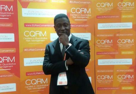 Dr Rexford Attah-Boakye in front of display boards at a conference