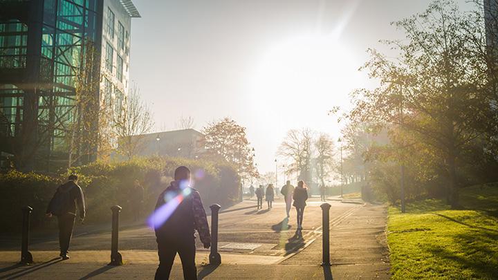 Students walking outside the Richmond building with sun in the background