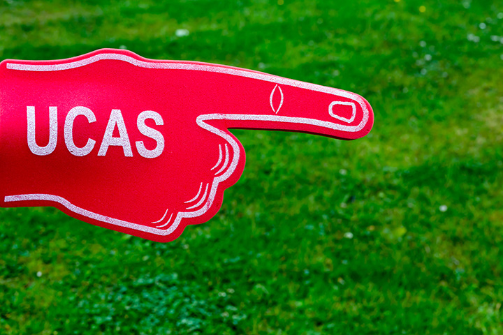 A red foam finger with the acronym 'UCAS' on it, with grass in the background