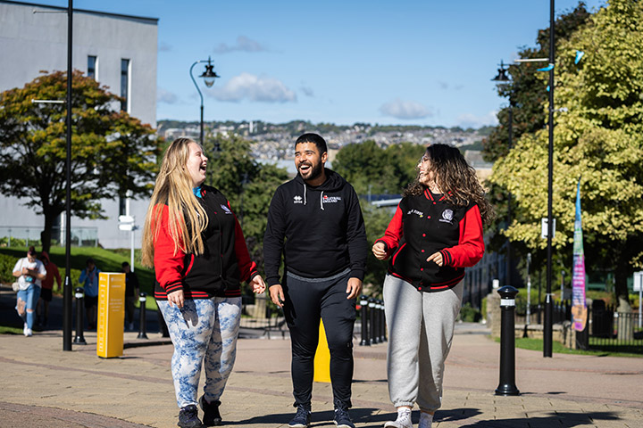 A group of three students walking around the University campus together and laughing