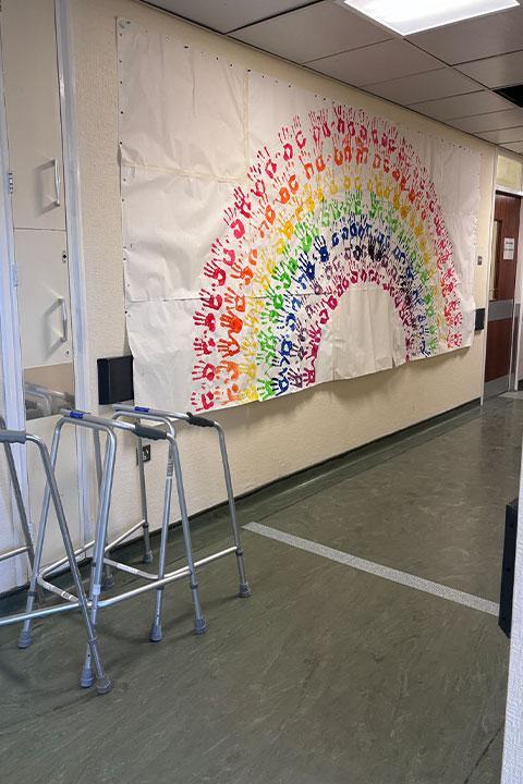 A mural of rainbow handprints on a wall.