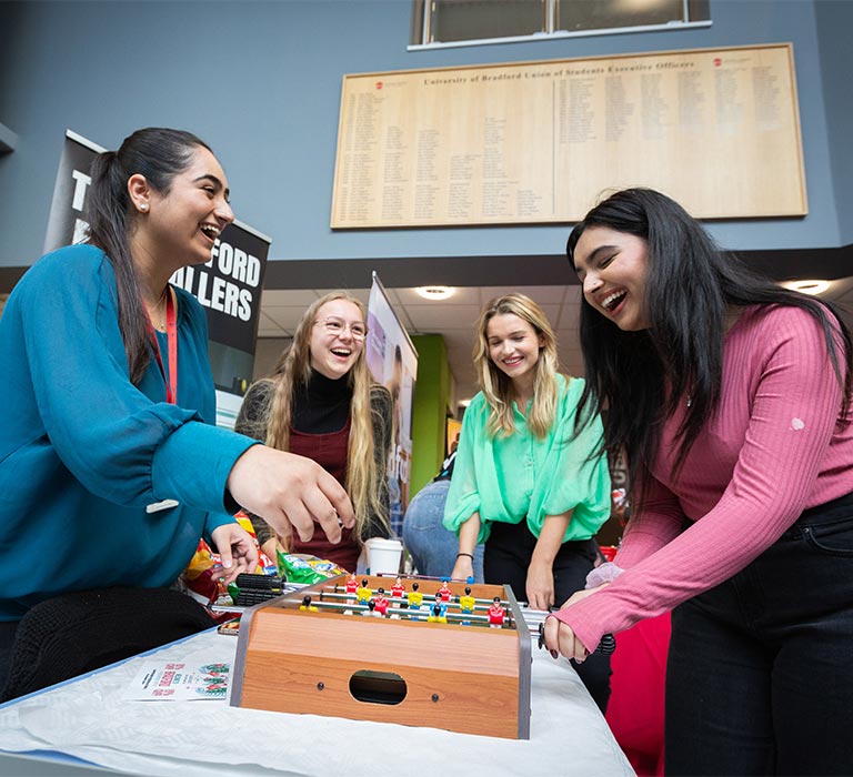 A group of student playing table top football and laughing.