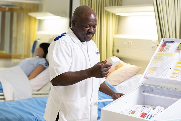 A student nurse dispensing medication from a medication cart.