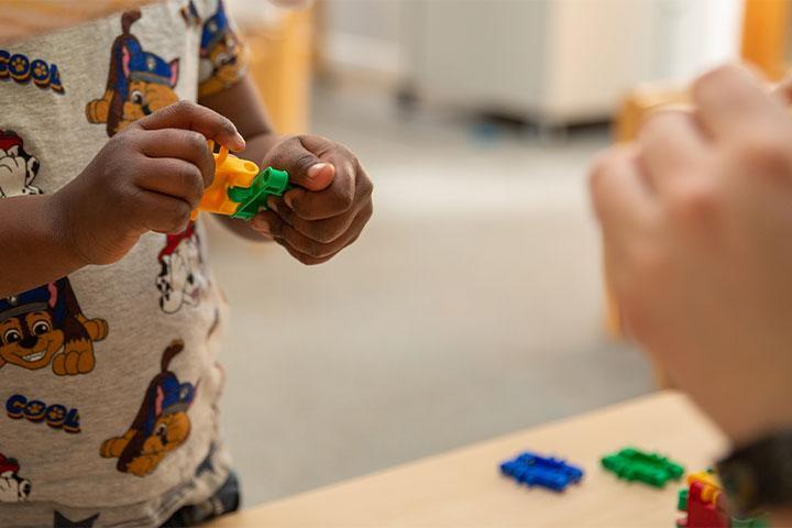 An adult and child playing with building blocks.