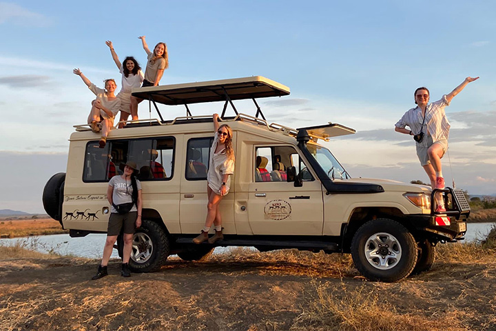 A student with their friends pose on a safari vehicle