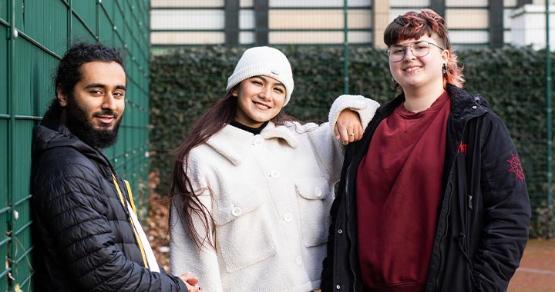 Three students smiling at the camera.