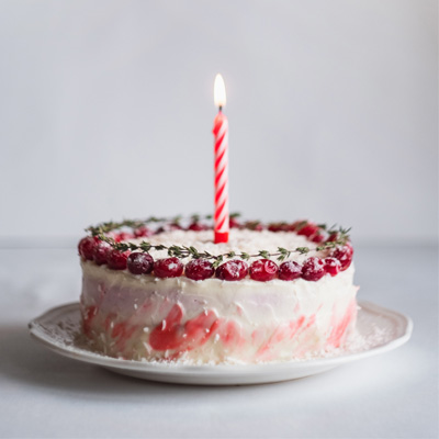 A colourful birthday cake with one candle in it.