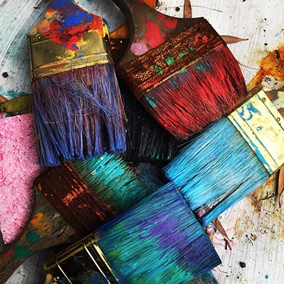 Several art paintbrushes with coloured paint on them.