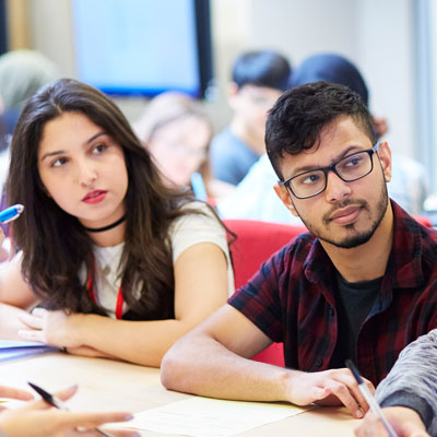 Two students concentrating on a lecturer in a classroom.