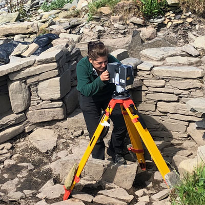 A person using archaeological surveying equipment outside.