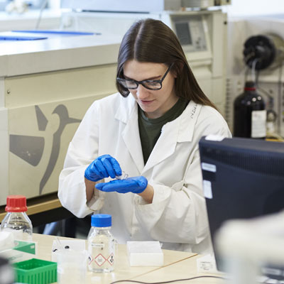 A person working in a lab wearing a white coat.