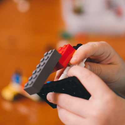 A child's hands building with LEGO.