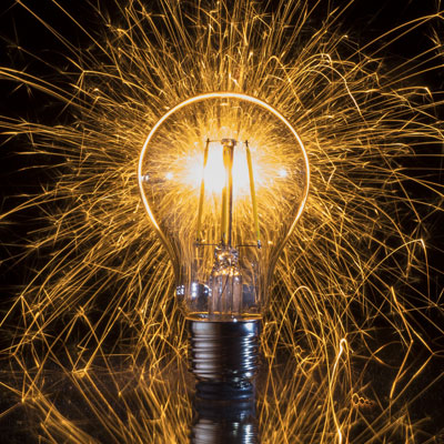 A lightbulb with several sparks emiting from it.