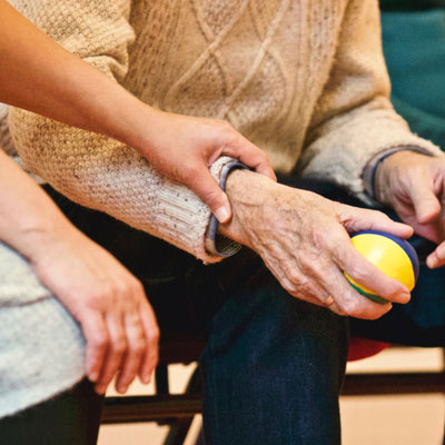 A young hand holding the wrist of an older person in a comforting way.