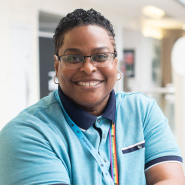 Dr Tiffany R Holloman posing and smiling in the atrium of Richmond Building