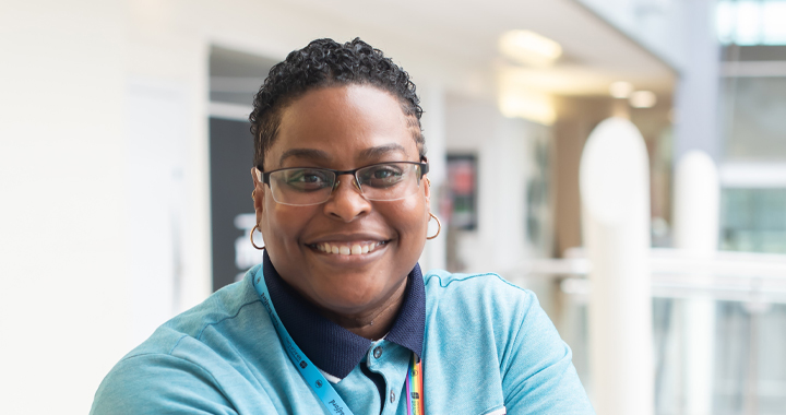 Dr Tiffany R Holloman posing and smiling in the atrium of Richmond Building