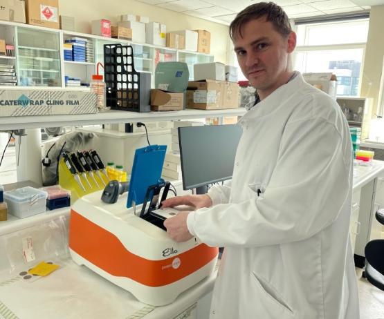 a scientist wearing a white coat is stood up in a laboratory working on an experiment