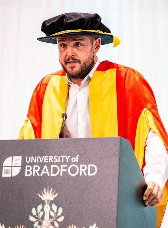 a person stands up at podium to give speech at graduation ceremony