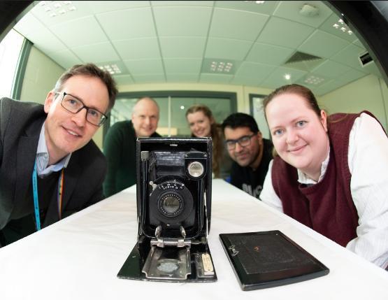 Academics peering at a 100-year-old camera about to go into a CT scanner