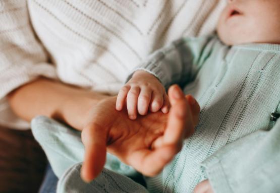 A mother holding a newborns hand