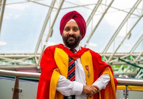 honorary graduate in gown stands in university atrium