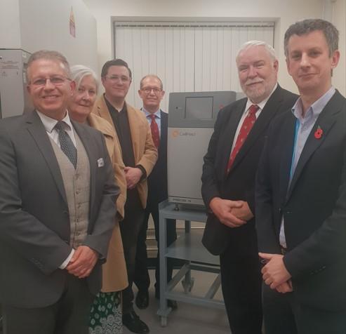 Academics and donors stood in front of a radiation source machine