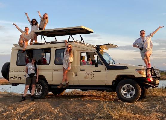 People riding on the outside of a Land Rover