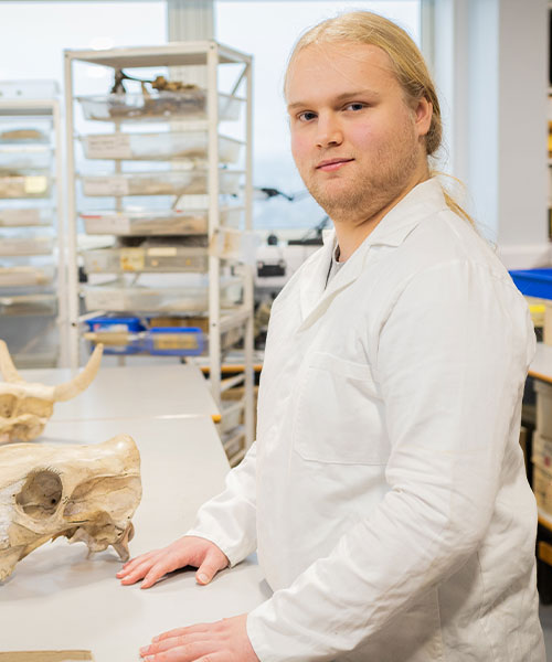 A student in an archaeology lab, smiling at the camera.