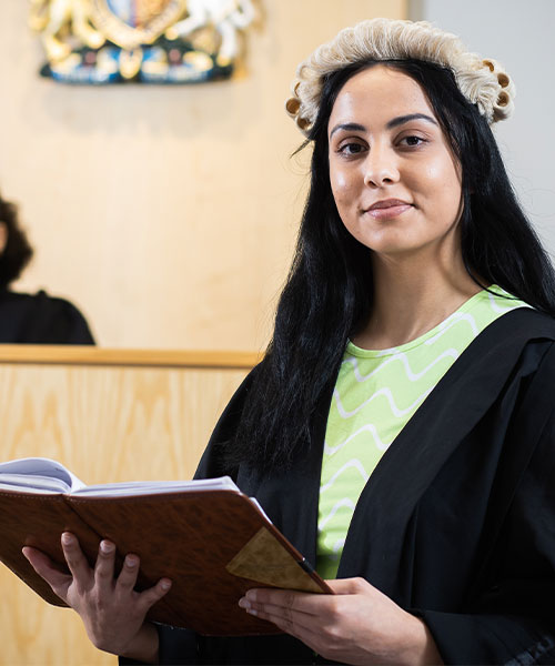 Two students in a mock court, smiling at the camera.